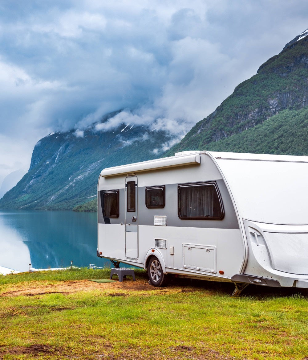 Camping Wohnwagen vor Bergen und einem ruhigen See